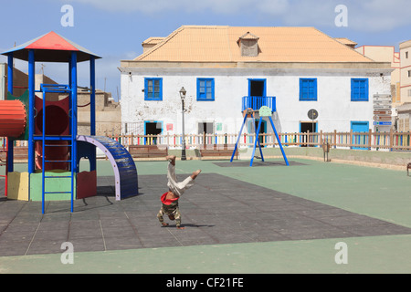 Happy barefoot local boy doing hand stands in children's playground in main square of Sal Rei Boa Vista Cape Verde Islands Stock Photo