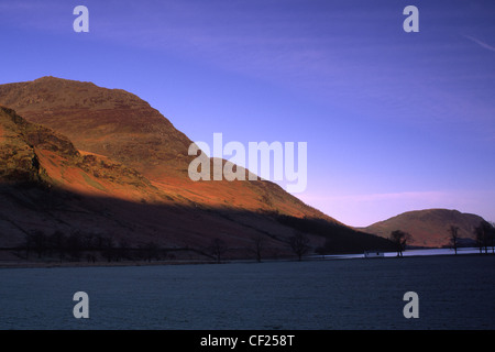 Early morning light illuminates the hills surrounding Lake Buttermere and Peggys Bridge. Stock Photo