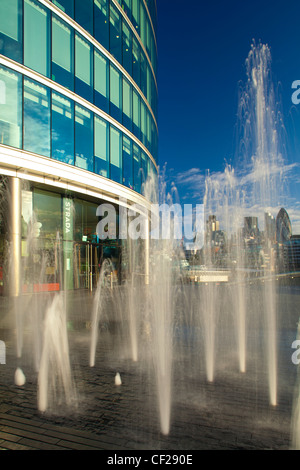 Water fountains near City Hall and the 'More London' development on the south bank of the River Thames, looking towards the land Stock Photo