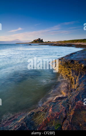 Bamburgh Castle, beach and dunes viewed shortly after sunrise from Harkess Rocks. Stock Photo