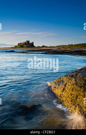 Bamburgh Castle, beach and dunes viewed shortly after sunrise from Harkess Rocks. Stock Photo