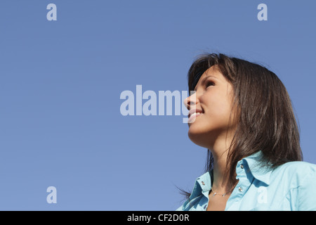 Portrait of a young woman against a blue sky with a lot of copyspace. Stock Photo