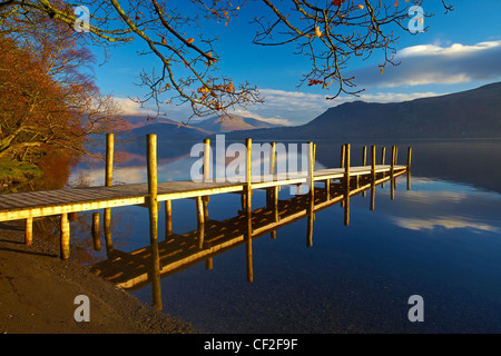 Autumnal view of Brandelhow Jetty reflected in the still water of Derwentwater in the Lake District National Park. Stock Photo