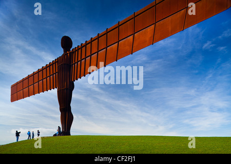 Tourists standing under the iconic Angel of the North statue by Antony Gormley. The 'Angel', built on a a former colliery pit he