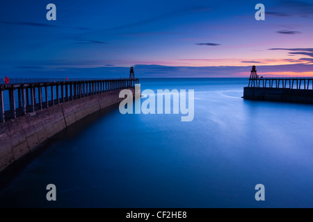 The entrance piers of Whitby Harbour at dawn. Stock Photo