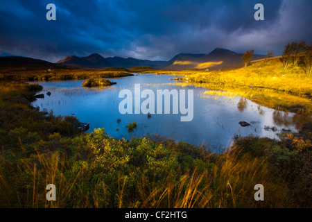 Lochan an Stainge located on Rannoch Moor with the dominating peak of the Black Mount and surrounding mountains in the distance. Stock Photo