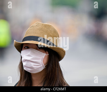 A young woman wearing a face mask to protect herself against catching swine flu. Stock Photo