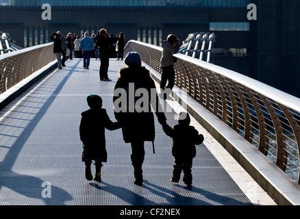 A mother and children crossing the Millennium Bridge over the River Thames. Stock Photo