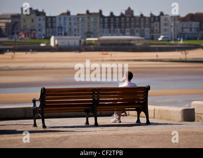 A man sitting on a bench at the end of the Harbour Arm in Margate. Stock Photo