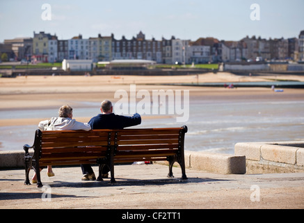 A couple sitting on a bench at the end of the Harbour Arm in Margate. Stock Photo