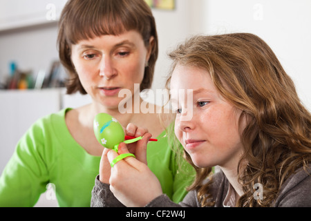 Mother and daughter sitting at home together and painting easter eggs Stock Photo