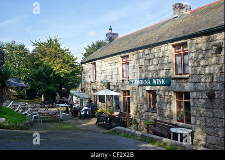 People sitting outside the Lamorna Wink pub. The Wink refers to smuggling and the sign that used to be made to mean contrband wa Stock Photo