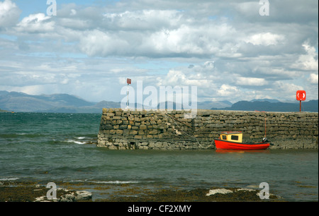 A small red boat moored by the harbour wall at Broadford on the Isle of Skye. Stock Photo