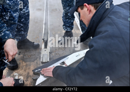 BREMERTON, Wash. (Feb. 28, 2012) – Airman Apprentice Mccord Brickle and Aviation Boatswains Mate (Equipment) 2nd Class Luke Hart perform maintenance on a waist catapult shuttle on the flight deck of the aircraft carrier USS Nimitz (CVN 68). The maintenance is part of Nimitz’ continuing effort to prepare for sea. Nimitz is making final preparations to return to sea. Stock Photo