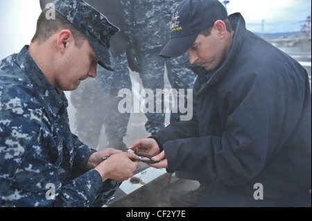 BREMERTON, Wash. (Feb. 28, 2012) – Airman Apprentice Mccord Brickle and Aviation Boatswains Mate (Equipment) 2nd Class Luke Hart perform maintenance on a waist catapult shuttle on the flight deck of the aircraft carrier USS Nimitz (CVN 68). The maintenance is part of Nimitz’ continuing effort to prepare for sea. Nimitz is making final preparations to return to sea. Stock Photo