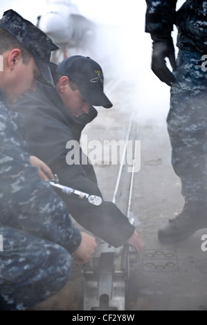 BREMERTON, Wash. (Feb. 28, 2012) – Airman Apprentice Mccord Brickle and Aviation Boatswains Mate (Equipment) 2nd Class Luke Hart perform maintenance on a waist catapult shuttle on the flight deck of the aircraft carrier USS Nimitz (CVN 68). The maintenance is part of Nimitz’ continuing effort to prepare for sea. Nimitz is making final preparations to return to sea. Stock Photo