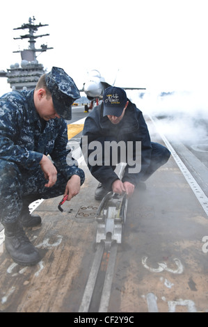 BREMERTON, Wash. (Feb. 28, 2012) – Airman Apprentice Mccord Brickle and Aviation Boatswains Mate (Equipment) 2nd Class Luke Hart perform maintenance on a waist catapult shuttle on the flight deck of the aircraft carrier USS Nimitz (CVN 68). The maintenance is part of Nimitz’ continuing effort to prepare for sea. Nimitz is making final preparations to return to sea. Stock Photo