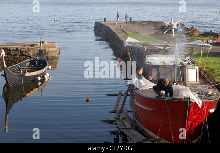 A fishing boat undergoing repair and replica Viking boat in Corrie Harbour on the Isle of Arran. Stock Photo