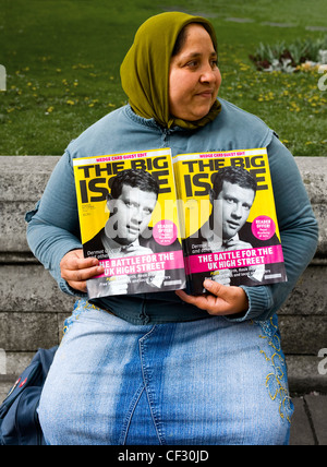 A woman selling copies of 'The Big Issue', a weekly magazine sold by street vendors offering homeless and vulnerable people the Stock Photo
