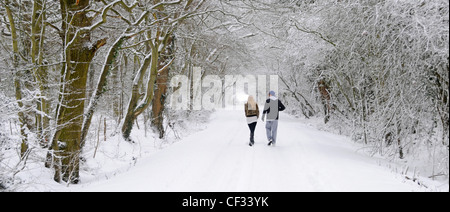 Young couple walking along country lane after heavy snowfall Stock Photo