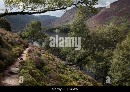 A pathway running along the heather clad hillside by Loch Muick in the Cairngorms National Park. Stock Photo