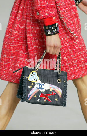 Chanel Paris Ready to Wear S S Close up of female models hand holding a black fabric purse appliqu detail of a rainbow, red Stock Photo