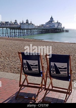 Two empty deckchairs on the Eastbourne promenade facing the beach and pier. Stock Photo