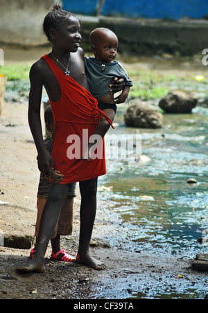 A smiling girl holding a baby in Kenema, Sierra Leone