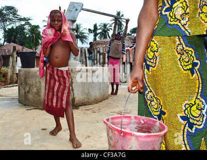 Children using a hand-pump well in a village near Kenema, Sierra Leone Stock Photo