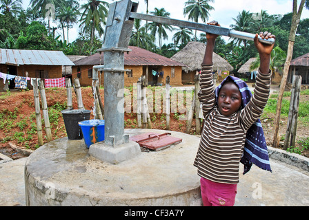 Children using a hand-pump well in a village near Kenema, Sierra Leone Stock Photo