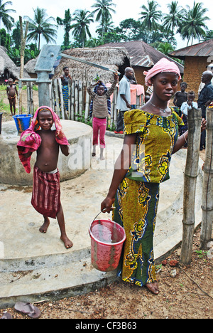 Children using a hand-pump well in a village near Kenema, Sierra Leone Stock Photo