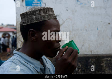 Man drinking tea from a plastic cup Stone Town Zanzibar Tanzania Stock Photo