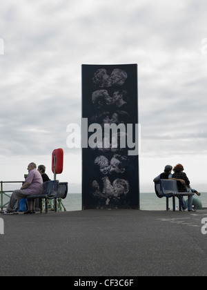 A sculpture of people kissing with two couples sitting either side on the water front in Brighton. Stock Photo