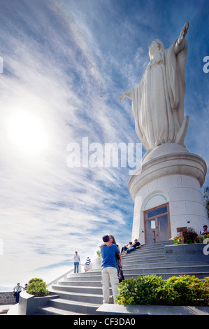 Santiago Chile, Cerro San Cristobal Hill. Happy couple kissing underneath the famous landmark the Blessed Virgin Mary in spring. Stock Photo