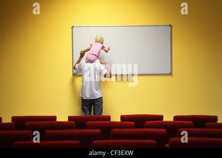 father and little girl in empty presentation hall. little girl is sitting on a father's neck. chair in out of focus. Stock Photo