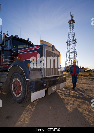 Truck parked in front of oil drilling derrick. Stock Photo