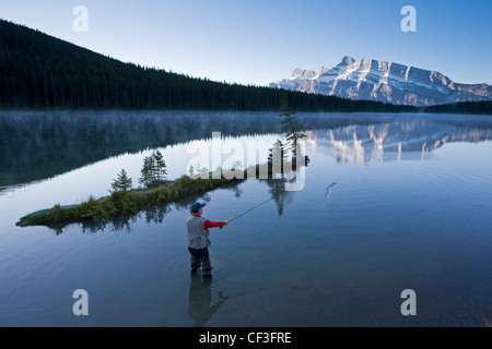 Middle aged male fly fishing in Two Jack Lake, Banff National Park, Alberta, Canada. Stock Photo