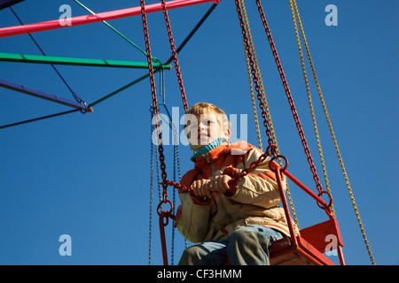 Portrait of boy seated in carousel. Bottom view on sunny autumn day. Stock Photo