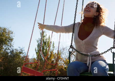 Happy girl riding on  carousel. Outdoor leisure on sunny autumn day. Stock Photo