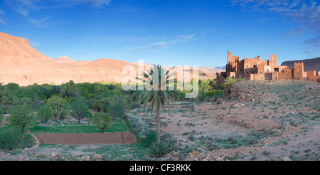 Kasbah Ellouze perched on a rocky outcrop overlooking the date palms and distant Atlas mountains. Stock Photo