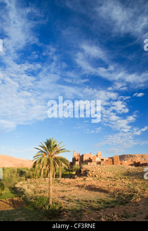 Kasbah Ellouze perched on a rocky outcrop overlooking the date palms and distant Atlas mountains. Stock Photo