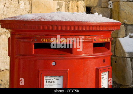 A red post box with a dusting of snow on top in York. Stock Photo