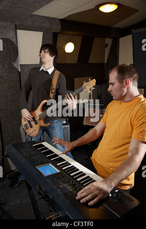 guitar player and keyboard player is working in studio. focus on distant part of synthesizer Stock Photo