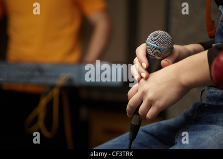 microphone in hand of vocalist girl. keyboard player in out of focus Stock Photo