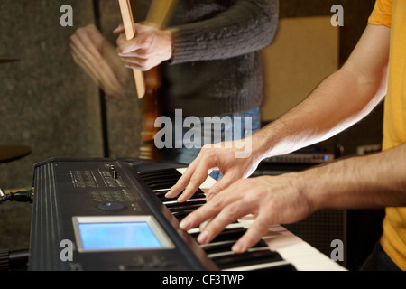 keyboard player playing in studio. guitar player in out of focus Stock Photo