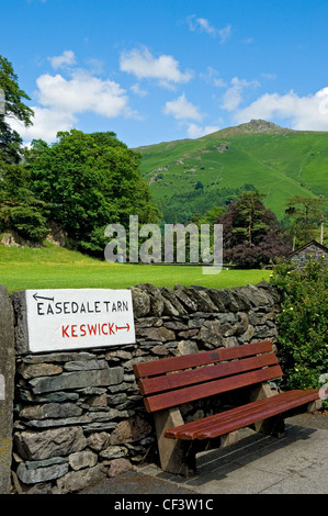 A hand carved sign with directions to Easedale Tarn and Keswick on a stone wall. Stock Photo