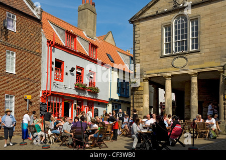 Visitors sitting at tables outside Arnie's coffee bar / bistro, next to the old Town Hall in Market Place. Stock Photo