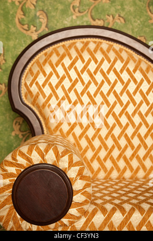Fragment of sofa against green wall. Interior in retro style. Vertical format. Stock Photo
