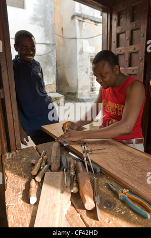 Carpenter carving an ornate frame for a bed Stone Town Zanzibar Tanzania Stock Photo