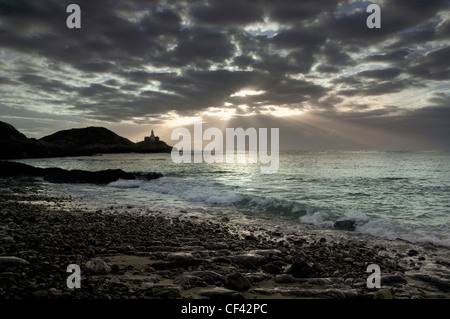 Rays of sunlight bursting through storm clouds over Mumbles Point at dawn. Stock Photo